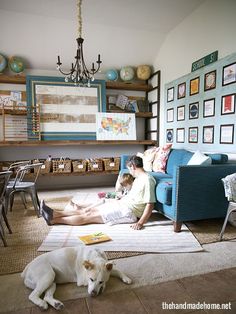 two people and a dog are sitting on the floor in front of a blue couch