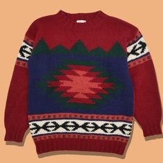 a red sweater with green, blue and white designs on the front is against an orange background