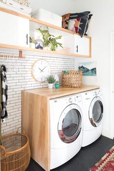 a washer and dryer sitting in a room next to a wall mounted clock