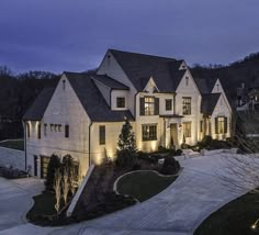 a large white house with lots of windows and lights on it's front yard