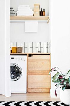 a white washer sitting next to a wooden cabinet in a room with black and white rug