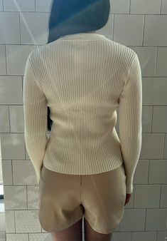 Your classic ribbed knit sweater with a twist. This beautiful off-white garment is cozy and stylish. The unique twist front detail adds a fashionable element to a timeless sweater, making it trendy and comfortable. It is a versatile choice for various occasions, from casual outings to dressier events. Fabric content: 50% rayon, 25% polyester, 22% nylon Washing instructions: dry clean only Imported Model: 5'3" wearing size extra small. Cream Ribbed V-neck Knit Top, Chic Cream Crew Neck Cardigan, Elegant White Ribbed Sweater, Trendy White Ribbed Sweater, Chic White Fine Knit Cardigan, Beige Stretch Ribbed Cardigan, Elegant Cable Knit Stretch Sweater, Elegant Stretch Cable Knit Sweater, White Chic Crew Neck Cardigan