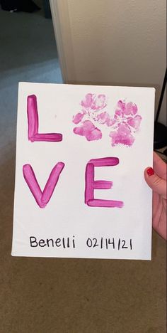 someone is holding up a card with the word love painted on it in pink ink