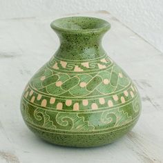 a green vase sitting on top of a white table