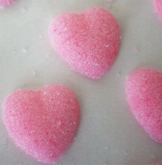 three heart shaped pink candys on a white surface