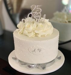 a white cake with flowers and a tiara on top is sitting on a table