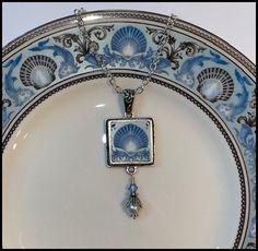 "BROKEN CHINA JEWELRY, SQUARE PENDANT NECKLACE, WEDGWOOD BLUE DOLPHINS PLATE Beautiful Shell Design Perfect Cruise Jewelry Made from a Vintage China Plate Pendant Measures 3/4\" X 2\", including Pearl and Crystal Dangle Includes Antiqued Sterling Bail and Silverplated Chain This listing is for a hand-crafted, \"broken china\" necklace. This piece has been created by artistically repurposing a vintage Wedgwood Blue Dolphins china plate. The china square pendant measures 3/4\" in width by 2\" in h Cruise Jewelry, Bridal Traditions, Broken China Crafts, Shabby Chic Jewelry, Wedgwood Blue, Broken China Jewelry, Antique Plates, China Jewelry, Broken China