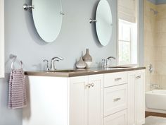 a bathroom with two sinks and three mirrors on the wall above them, along with a bathtub