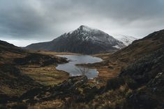 the mountains are covered in snow and brown grass, with a body of water below