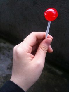 a person holding a red lollipop in their hand