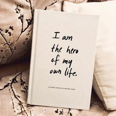 a book sitting on top of a bed next to two pillow cases with writing on them