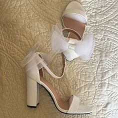 a pair of white high heeled shoes on top of a bed