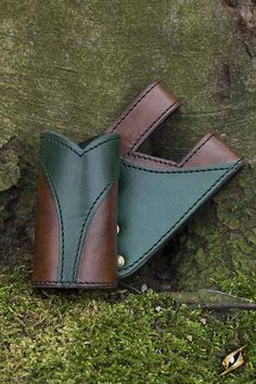 a pair of green and brown leather shoes sitting on top of a tree trunk next to a knife