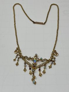 "Antique Art Nouveau 9Kt Opal, Ruby and Pearl Necklace. Approximate measurements: length of chain end to end 14 1/2\", center piece 70mm x 41mm. This 9Kt Opal, Ruby and Pearl necklace has been professionally appraised for $4500.00 and that written appraisal will accompany the necklace when sold. Since I am not an expert regarding this item, I have relied on the expertise of the certified professional appraisal. The following details about this Art Nouveau necklace are from a Certified Gemologist Antique Yellow Gold Jeweled Necklaces, Antique Multi-stone Gold Jewelry, Antique Gold Multi-stone Jewelry, Antique Yellow Gold Necklaces With Jewels, Ornate Jeweled Necklaces For Formal Occasions, Hallmarked Pendant Costume Necklace, Elegant Yellow Gold Jeweled Necklace, Costume Jewelry Pendant Necklace, Antique Yellow Gold Jeweled Jewelry