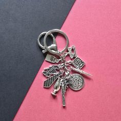 a metal keychain with charms on it sitting on a pink and black surface