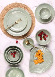 a table topped with plates and bowls filled with food next to a bowl full of cherries