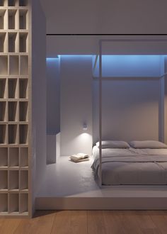 a white bed sitting next to a tall book shelf filled with books on top of a hard wood floor