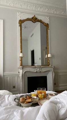 breakfast is on the bed in front of an ornate mirror