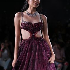 a woman in a purple dress on the runway