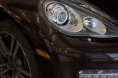 the front end of a black car with chrome rims and headlamps on