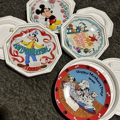 four mickey mouse plates sitting on the floor