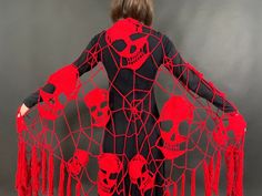 a woman in a black and red costume with skulls on her body, holding onto a net