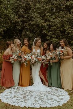 a group of women standing next to each other holding bouquets in front of trees