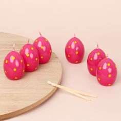 pink candles with yellow dots on them sitting on a wooden plate next to chopsticks