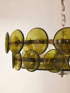 a chandelier made out of wine glasses hangs from a chain on a wall