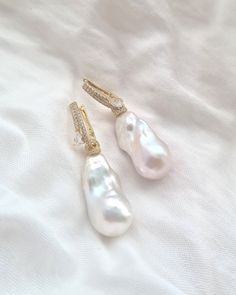 "Lustrous, mirror-like glowing, and showcasing the natural, pure white color in their astonishing shape, these large baroque pearl earrings are a true standout. The classy and elegant design is matched with high lustre and radiance, allowing them to make a statement without being overstated. These earrings are perfect for both everyday wear and special occasions alike. These stunning 2-way white Baroque Pearl earrings are made with glamorous gold vermeil cubic zirconia ear hoops and a pair of highly lustrous baroque pearls. You can wear just the ear hoops for a simple ensemble, and for a bespoke appearance, you can attach the gorgeous baroque pearls. No two pearls are exactly the same. Embrace the perfect imperfection. Embrace uniqueness. Embrace individuality.  ♡  Earrings FWPE 065_1 ♡  ✧ High Luster White Pearl Earrings For Evening, White High Luster Pearl Earrings For Evening, White High Luster Drop Pearl Earrings, Fine Jewelry White Bridal Earrings For Evening, White Fine Jewelry Bridal Earrings For Evening, Luxury White Bridal Earrings For Evening, Exquisite White Pearl Earrings For Party, White High Luster Pearl Drop Earrings, Luxury White Drop Earrings