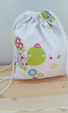 Bolsa mochila para bebe. Muy practica, puede usarse en muchas situaciones: para llevar la ropa de cambio a la guarderia, el sandwich, o los accesorios para el bebe (pañales, etc.). Es la bolsa perfecta para el dia a dia. Se puede lavar perfectamente en la lavadora. Muy suave y manejable. Hecha con tela estampada con tortugas y flores de colores sobre fondo blanco.Sin forrar. Las medidas son: Para niño: Ancho: 26 cm Alto: 30.5 cm Para adulto: Alto: 42,5 cm Ancho: 35 cm Cute Pouch Bags For Back To School, Cute Back To School Pouch Bag, Cute Tote Diaper Bag, Playful Softback Bags For Back To School, Casual Standard Backpack For Playtime, White Playful School Bag, Green Cotton Standard Backpack, White Playful School Bags, Playful White School Bag