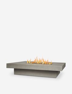 a concrete fire pit sitting on top of a white table with flames coming out of it