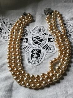 "Beautiful 3 strand knotted-in-between faux pearl necklace with a rhinestone disc clasp closure. These necklaces were made in Providence, Rhode Island, by a company that was commissioned by Danbury Mint to make replicas of a style necklace worn by Jacqueline Kennedy and was sold through Danbury Mint. These are faux glass pearls in a champagne color. In very good vintage conditions Measurements are 16\" around the neck. The mannequin it is shown on has a 12\" neck. Feel free to convo me with any Vintage Multi-strand Pearl Necklace For Formal Occasions, Formal Multi-strand Beaded Pearl Necklace, Vintage Double Strand Pearl Necklace For Anniversary, Vintage Single Strand Pearl Necklace For Wedding, Multi-strand Pearl Necklace For Formal Occasions, Formal Costume Multi-strand Pearl Necklace, Vintage Pearl Necklace With Round Beads For Weddings, Adjustable Formal Pearl Necklace, Formal Adjustable Pearl Necklace