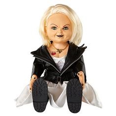 a doll is sitting on the ground with her legs crossed and eyes wide open, wearing a black leather jacket