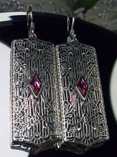 "Earrings Description Made To Order Inspired by the Art Deco movement of the 1920s and 30's, I now offer these lovely Antique reproduction earrings in sterling silver (Recast from an Art Deco pin). Each stunning 1ct flawless Man-made/Simulated Red Ruby gemstone is 8mm long by 4mm in width. The gemstones have perfect color and clarity. The earrings are 2 1/8th inches long and 9/16th\" at their widest point. Notice the beautiful design of the Deco filigree setting. A gift box is included and all i Antique Nickel-free Earrings For Party, Ornate Red Earrings For Party, Ornate Red Filigree Earrings, Ornate Red Earrings For Formal Occasions, Red Filigree Dangle Earrings, Red Victorian Jewelry For Evening, Red Filigree Drop Earrings, Vintage Party Earrings With Intricate Design, Ornate Handmade Evening Earrings