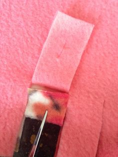 a pair of scissors is cutting through the fabric to make a piece of pink material