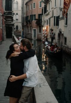 a man and woman embracing on a bridge over a canal in venice, italy with gondoli hanging from the buildings