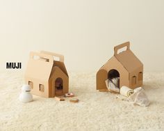 two cardboard houses sitting on top of a white carpet next to each other with the words jum written above them