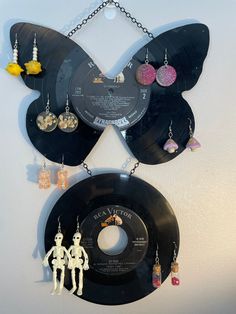 two vinyl records are hanging on the wall with earrings attached to them, and one is shaped like a butterfly