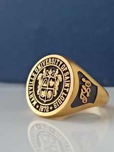 a gold and black ring with the seal of university of pennsylvania on it's side