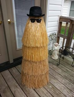 a man in a straw hat and sunglasses standing on a porch with a fake grass skirt