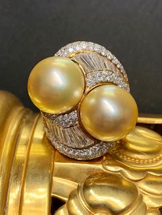 If you have ever wanted a ring with a presence, look no further. This fabulous piece is done in 18K yellow gold and set with approximately 4.50cttw in G-I color Vs1-Si1 clarity round and oversized, tapered baguette diamonds. Sitting next to each other are two natural golden South Sea pearls measuring 13mm and 13.40mm. What an incredible look! Dimensions/Weight .9" wide by 1.1" top to bottom. Size 5 3/4 (sizable). Weighs 15.3dwt Condition Light scuffs on the bottom of the shank, but in perfectly Luxury Yellow Diamond Ring Hallmarked, Luxury Gold Pearl Ring With High Luster, Luxury Gold Rings With High Luster, Luxury Yellow Diamond Hallmarked Ring, Luxury High Luster Gold Pearl Ring, Luxury High Luster Gold Rings, Exquisite Gold Diamond Ring Gia Certified, Yellow Gold Diamond Rings With High Luster, Luxury Oval Pearl Ring With Brilliant Cut