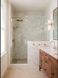 a bathroom with a walk in shower next to a double sink vanity and wooden cabinets