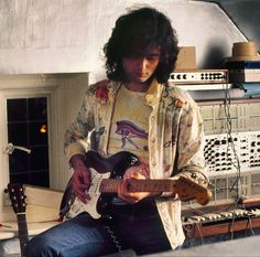 a man sitting on top of a chair holding a guitar in his hand and looking at it