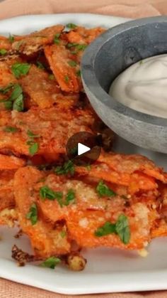 some food is on a white plate with a small bowl and dip in the middle