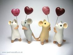 three small figurines are holding hearts in the shape of mice, one with a heart on its tail