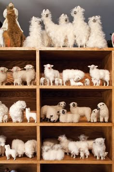 a wooden shelf filled with lots of white sheep and lamb figurines on top of it