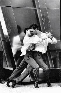 black and white photograph of two people dancing in front of a wall with large mirrors