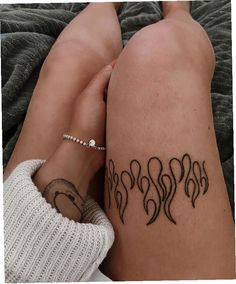 a woman's legs with tattoos on them and her hand resting on the leg