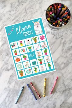 a printable llama bingo game with crayons on the table next to it